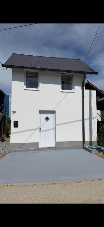 a white house with a door with a black roof at Vikendica za odmor in Kloštar Ivanić