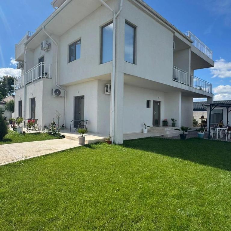 a large white house with a lawn in front of it at Casa AdiMan in Vama Veche