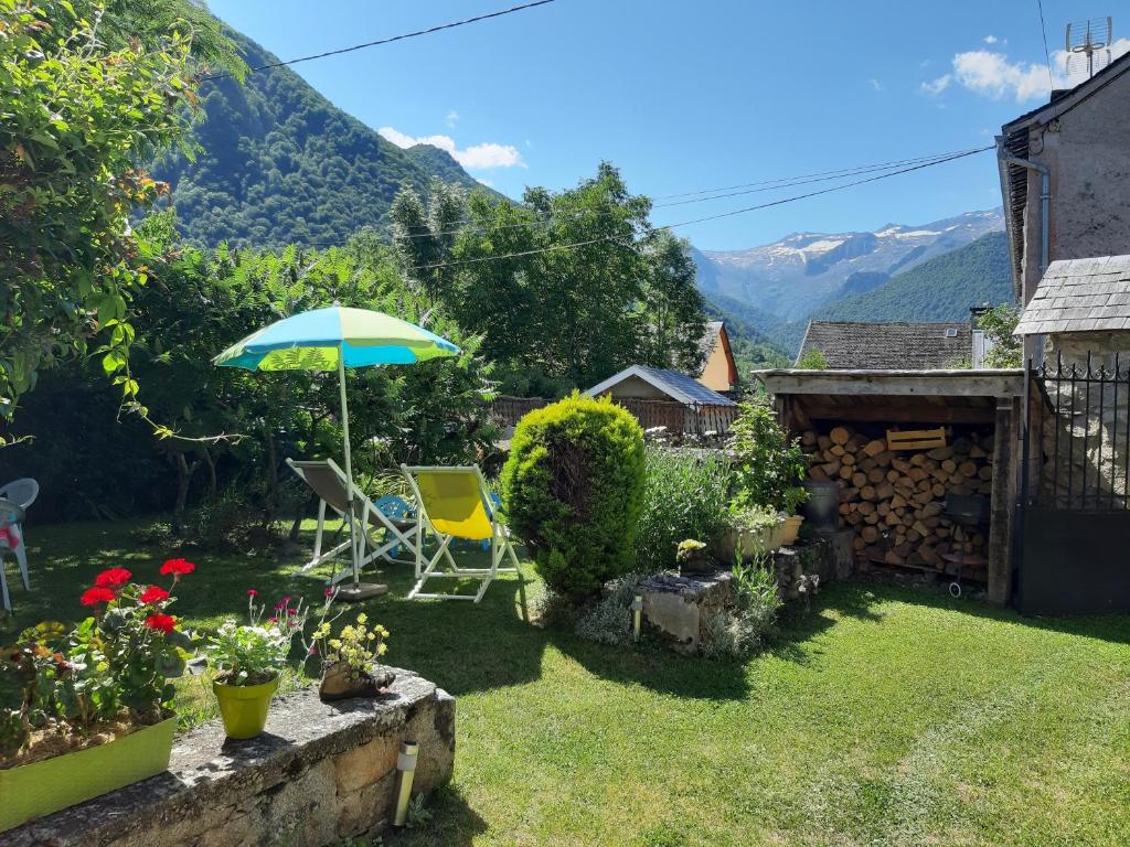 a garden with an umbrella and chairs and flowers at Gîte Pyrénées Ariège Ustou in Ustou