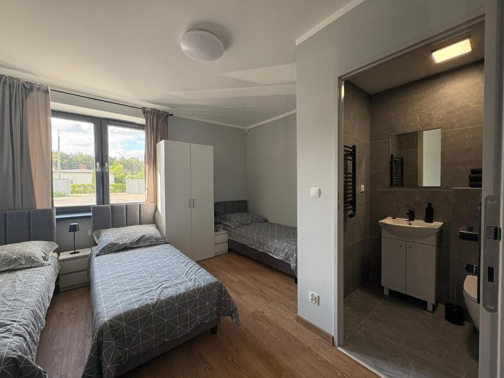 a bedroom with two beds and a sink and a mirror at Horiza Białe Błota in Białe Błota
