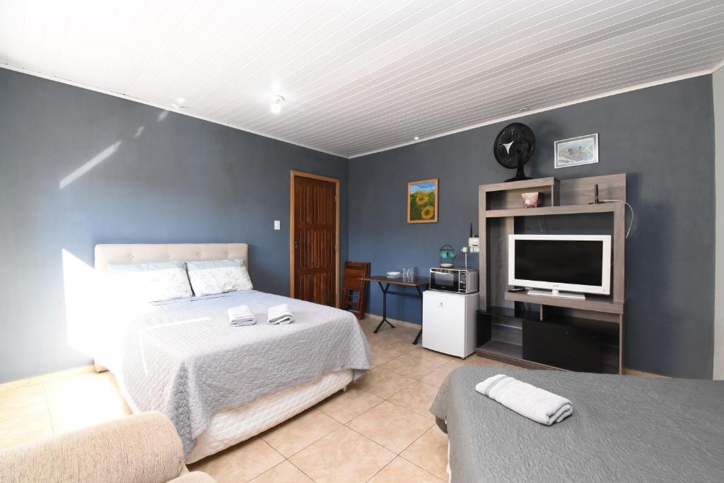 a bedroom with a bed and a flat screen tv at Suite/loft Jardim Botanico in Curitiba