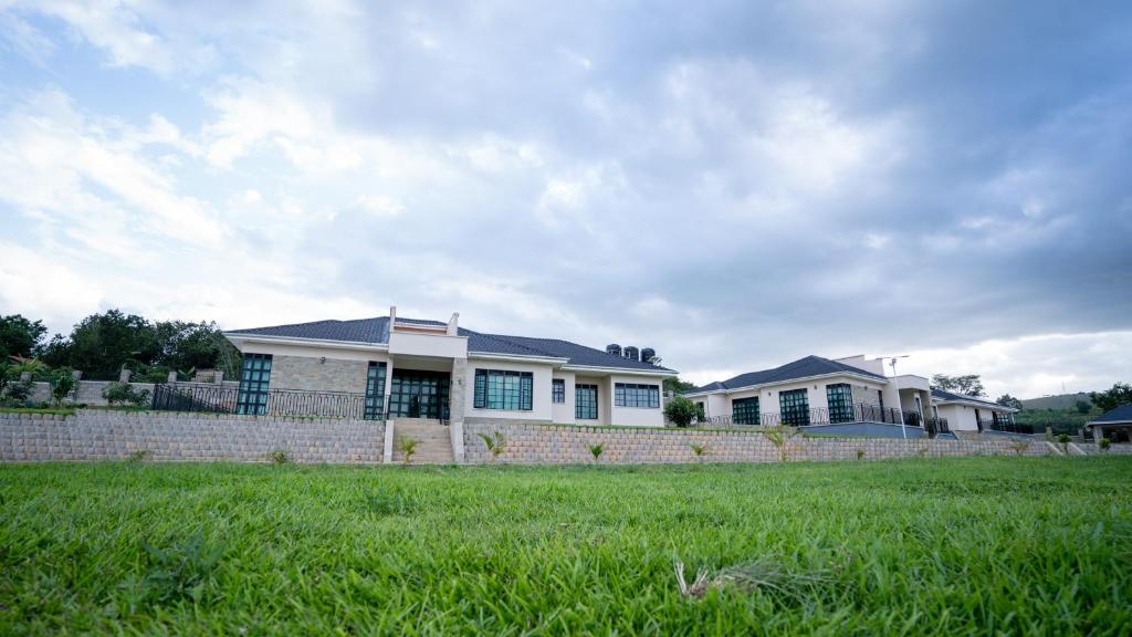 a house with a brick fence and a grass field at Bella Vista Villas Ltd in Mbarara