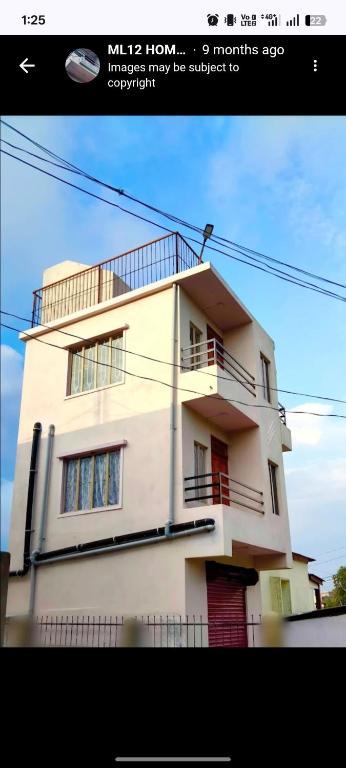 a large white house with a balcony on top of it at ML 12 HomeStay in Jakrem