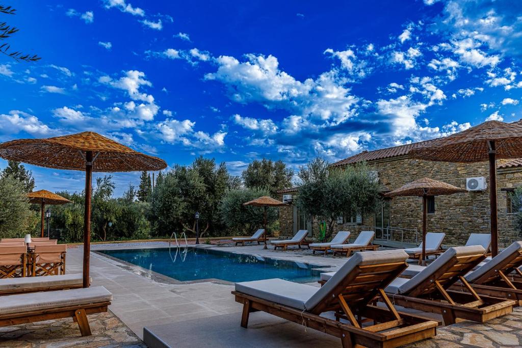 a swimming pool with lounge chairs and umbrellas at Penelopes Rhapsody Resort in Missolonghi