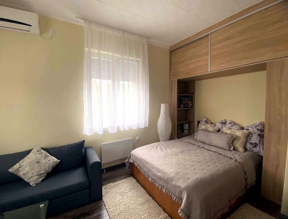 a bedroom with a bed and a couch and a window at Purple Madame in Balatonszárszó