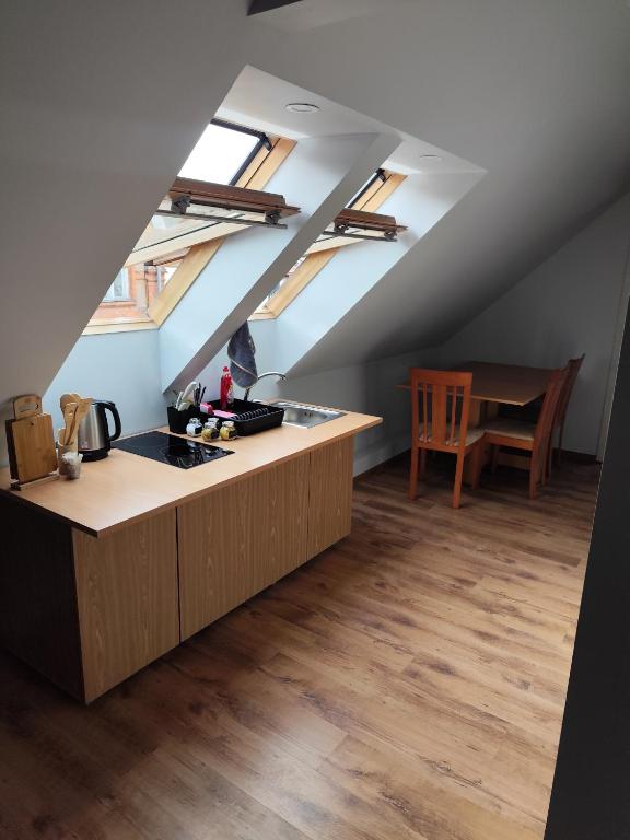 an attic kitchen with a counter and a table at Centro-loftas in Telšiai