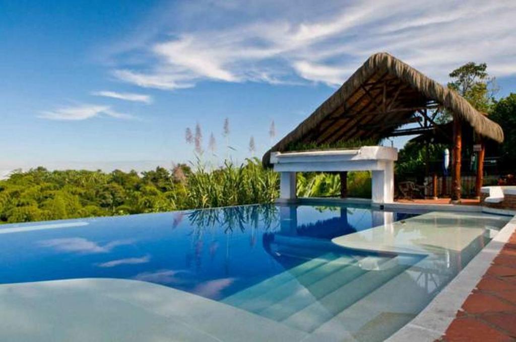 a large swimming pool with a gazebo at Hotel Hacienda Combia in Armenia