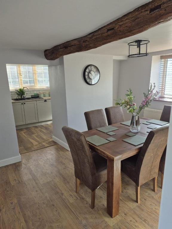 a dining room table with chairs and a clock on the wall at 3 bed detatched cottage with onsite parking in Rotherham