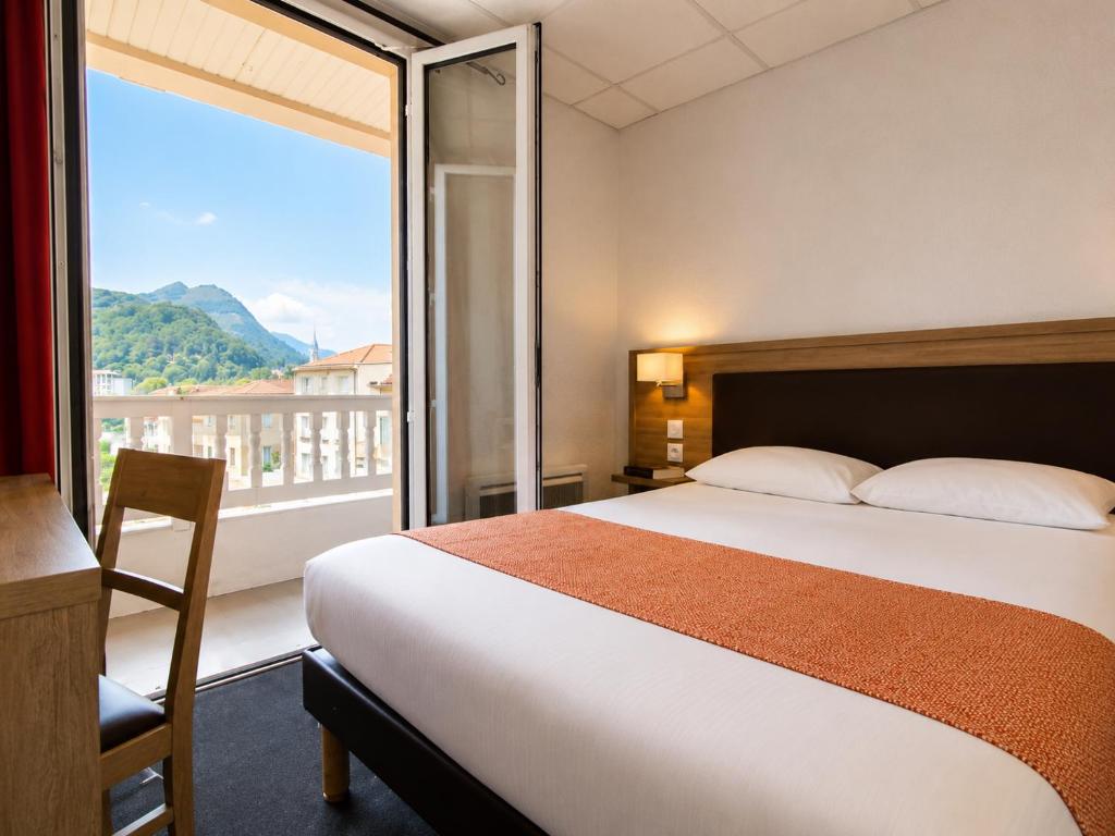 a hotel room with a bed and a large window at Hôtel Hélianthe in Lourdes