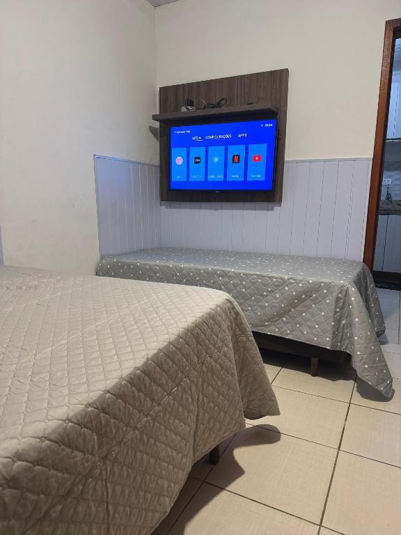 a room with two beds and a tv on the wall at Casa Completa in Curitiba