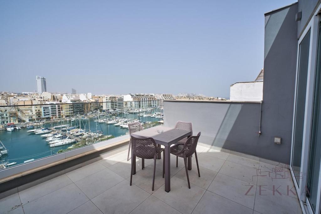 a table and chairs on a balcony with a view of a harbor at Beautiful View, 3 Bedroom Spacious Apartment in Tal-Pietà