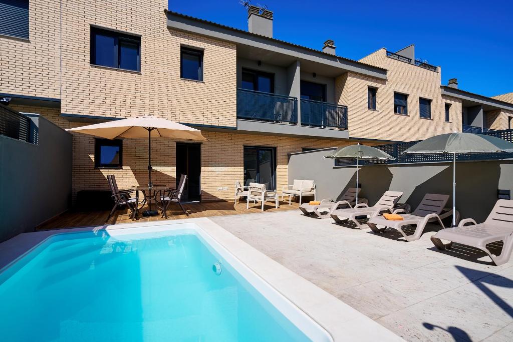 a swimming pool with chairs and umbrellas next to a building at Sun&Fun Villa in Vinarós