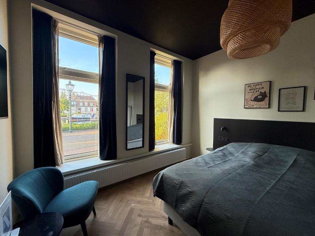a bedroom with a bed and a chair and windows at Logement Langestreek in Lemmer