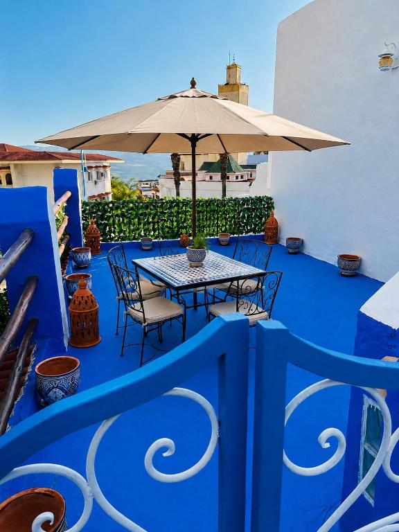 a table with an umbrella on a blue deck at Casa Inass blue in Chefchaouen