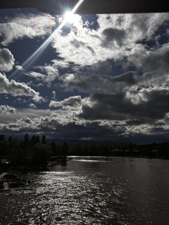 a cloudy sky with the sun on a river at THE INN Bigfork Bay in Bigfork