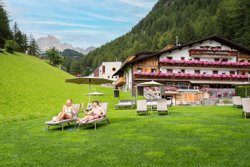 two women sitting on lawn chairs in front of a building at Hotel Jägerheim 3S in Selva di Val Gardena
