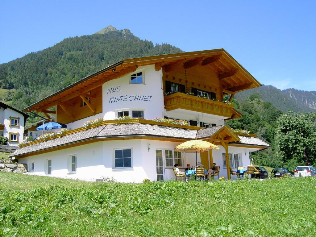 ein großes Gebäude mit Balkon und Sonnenschirm in der Unterkunft Haus Muntschnei in Sankt Gallenkirch