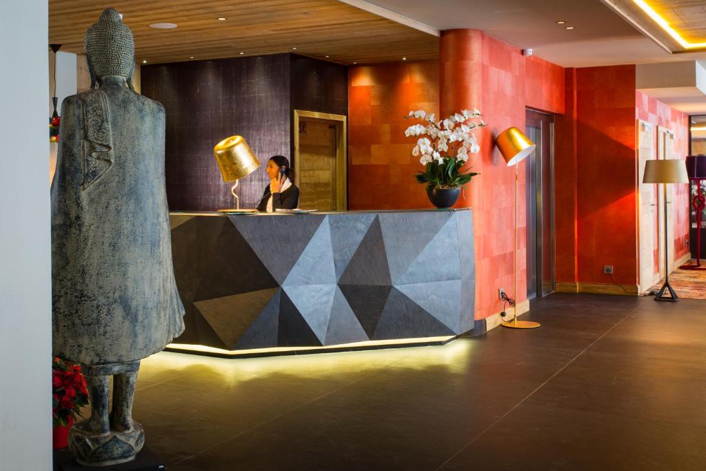 a woman sitting at a counter in a lobby at Hôtel Taj-I Mah by Les Etincelles in Arc 2000