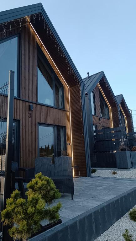 a house with a wooden facade with a patio at Domki Pod Łysicą- basen jacuzzi sauna in Krajno Pierwsze