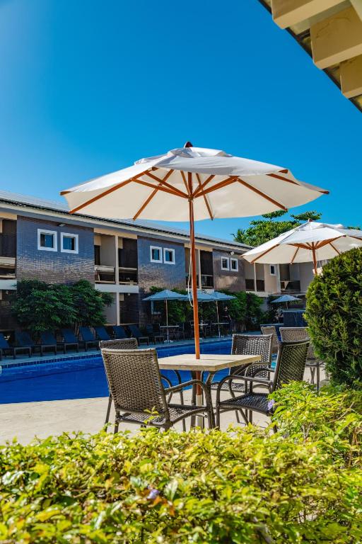 a table and chairs with an umbrella next to a pool at Safira Praia Hotel in Porto Seguro