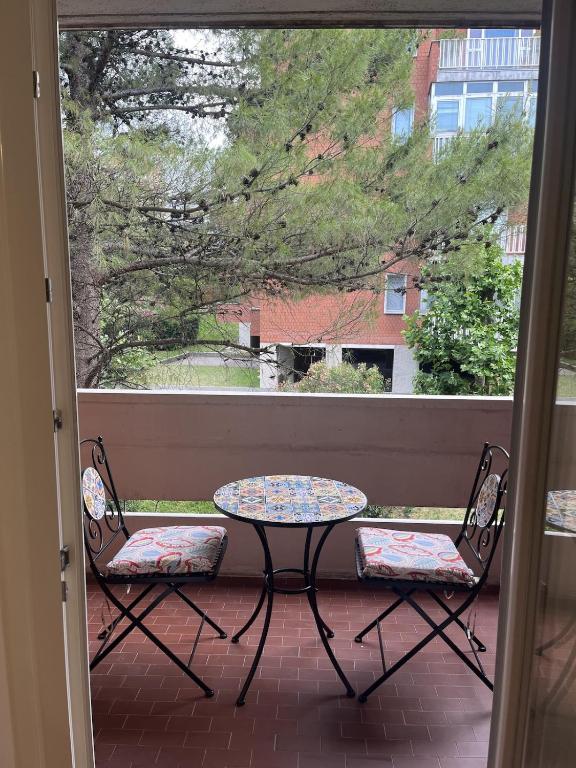 a table and two chairs on a porch with a window at Sea & Books Studio in Trieste