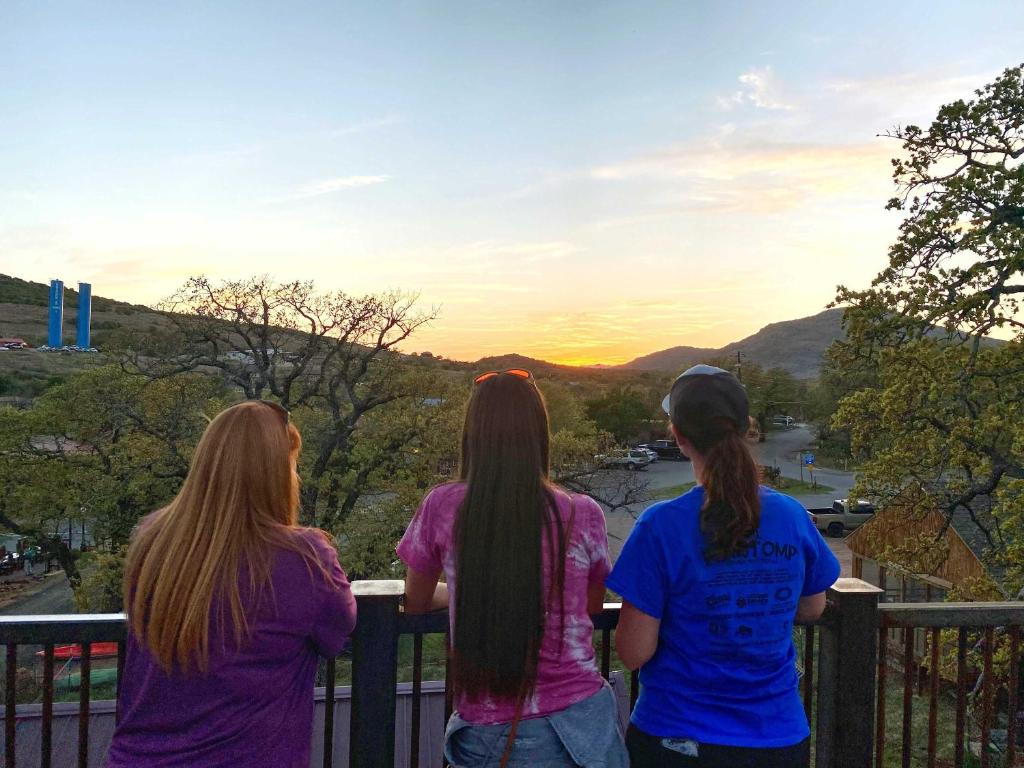 three girls standing on a balcony looking at the sunset at HT Innhabit rooftop view suite in Medicine Park
