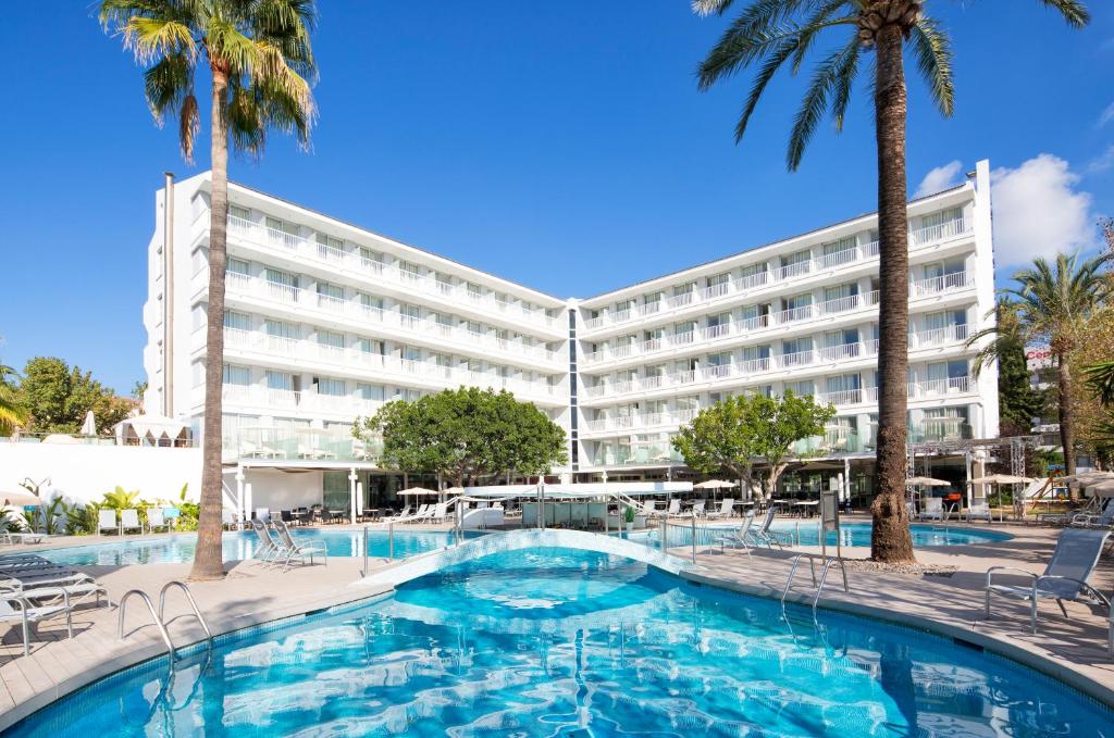 a hotel with a large pool and palm trees at JS Sol de Alcudia in Port d'Alcudia