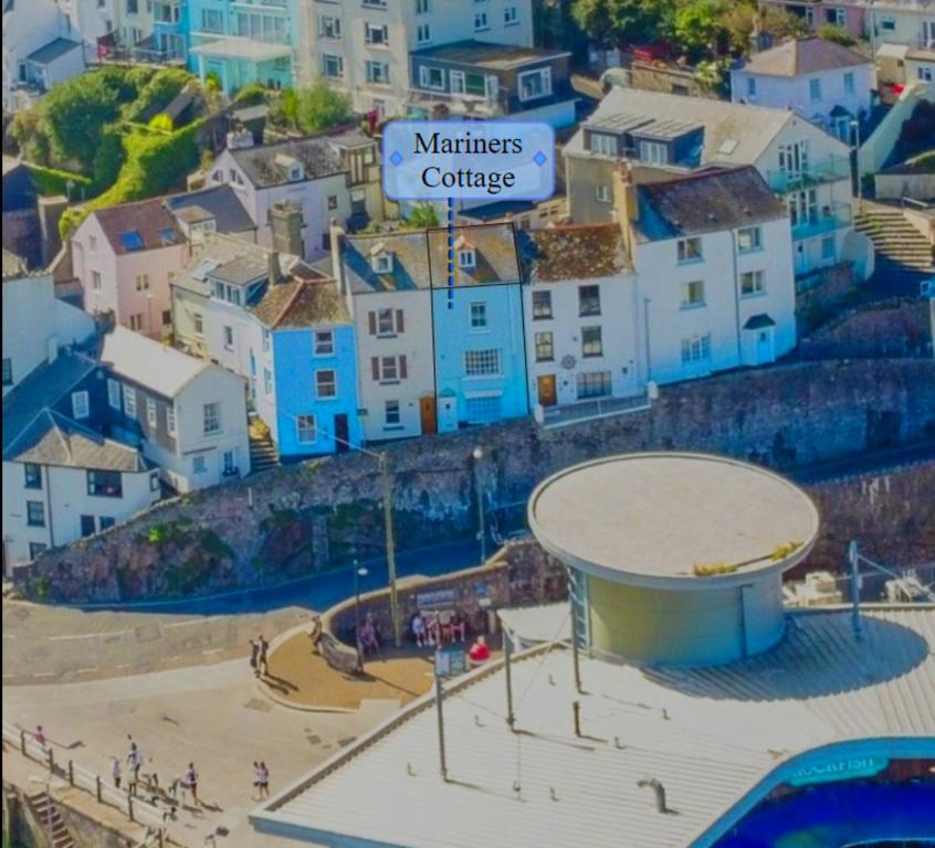 a city with blue buildings and a volleyball court at Mariners Cottage - Wake Up to Uninterrupted Sea Views in Brixham