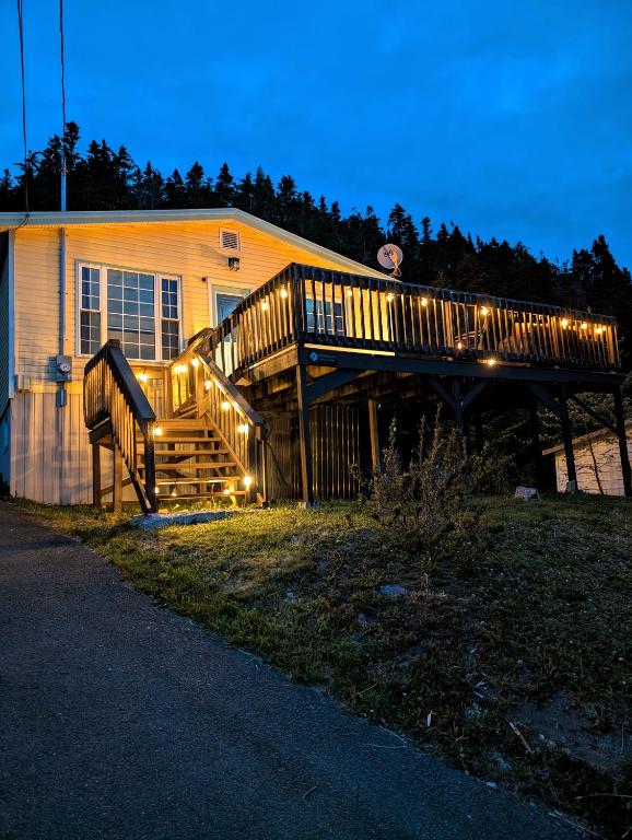 a house with a deck with lights on it at Finnegan's Cottage in Placentia