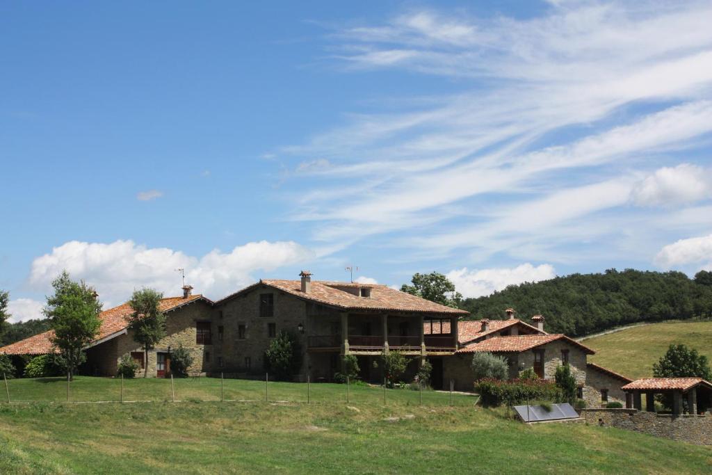 duży dom na wzgórzu z zielonym polem w obiekcie Mas la Serra w mieście Rupit