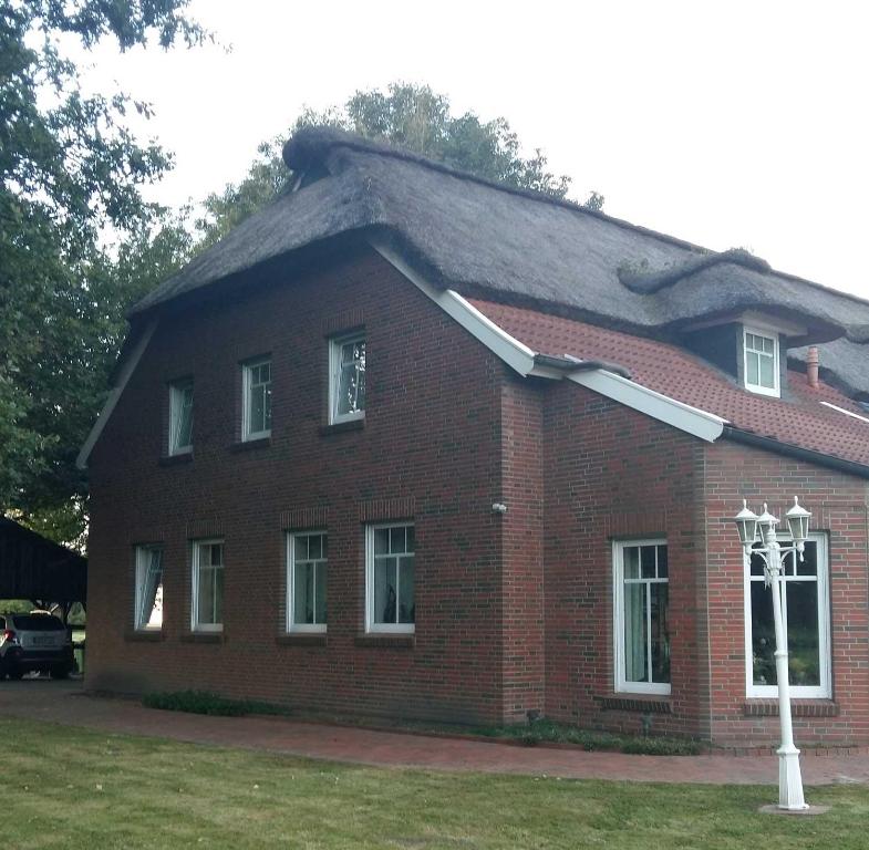 a red brick house with a gambrel roof at Ferienhof-Stoertebeker in Leybuchtpolder