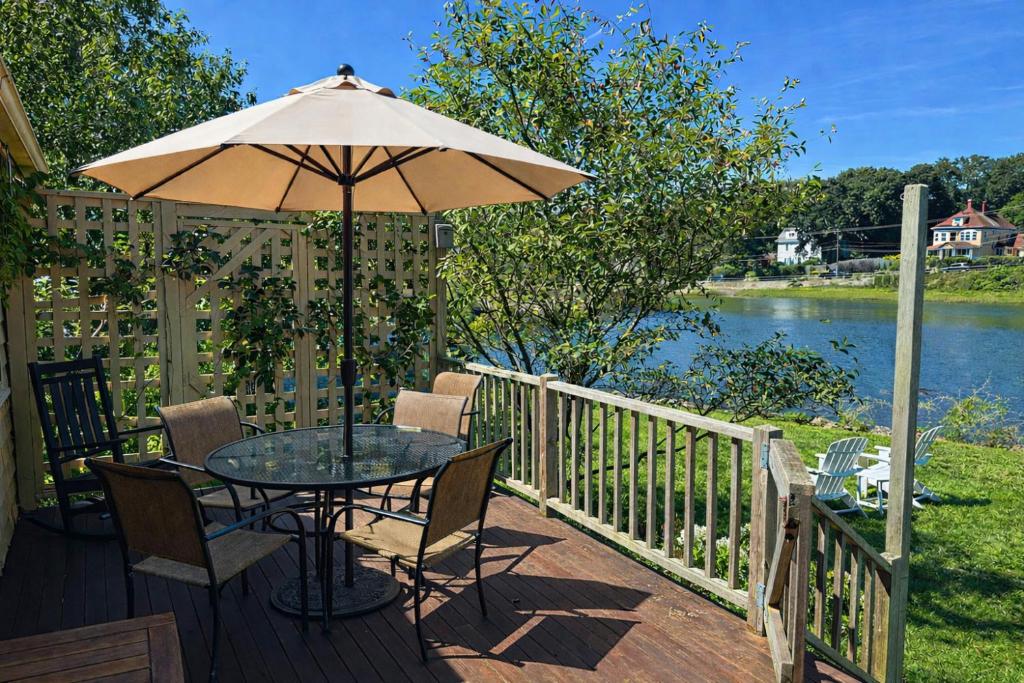 a table with an umbrella on a deck next to a river at River Watch in Gloucester
