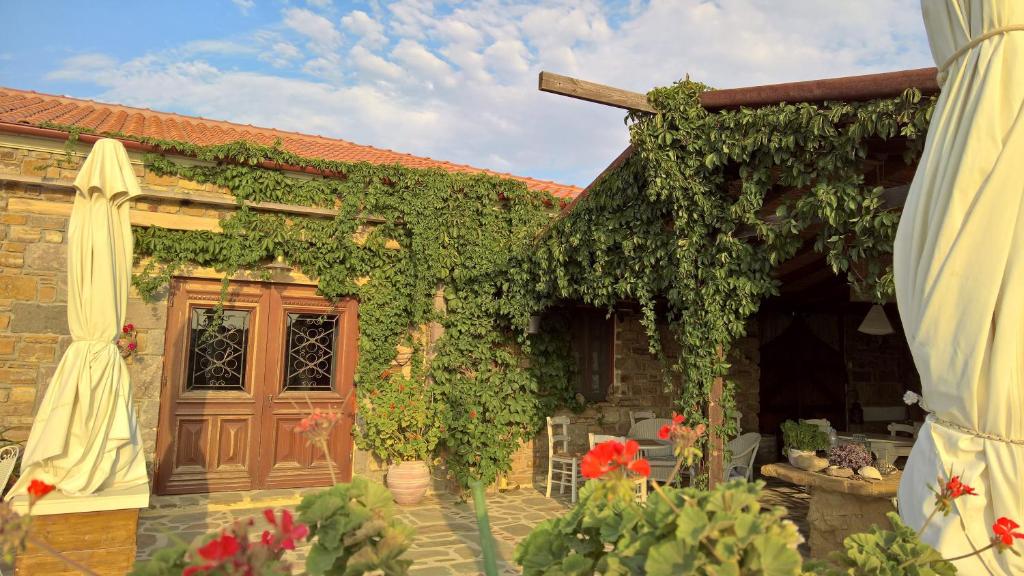 a house covered in ivy with a wooden door at Ethaleia Hotel in Moúdhros