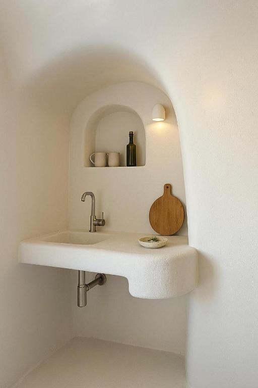 a bathroom with a sink in a white wall at Urano Cave Suites in Santorini