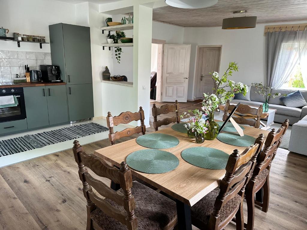 a dining room table with chairs and a kitchen at Upeskrastu mājas in Vilcāni