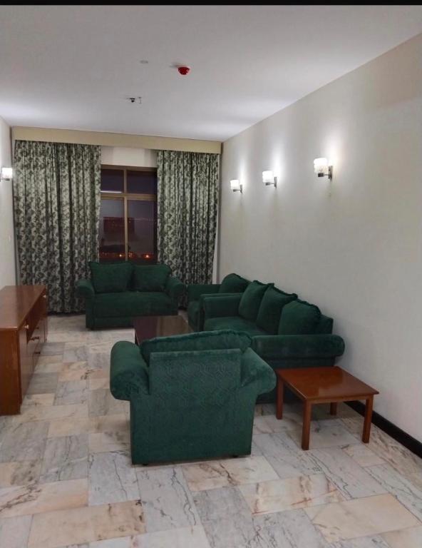 ein Wohnzimmer mit grünen Sofas und einem Tisch in der Unterkunft Private flats in Salalah