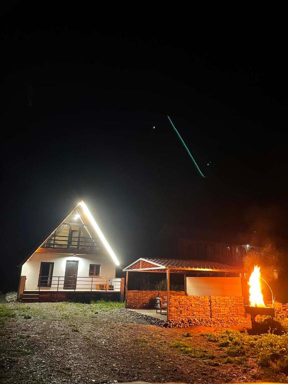 a house with a fire in front of it at night at kazbegi - Sno Mountain House in Sno