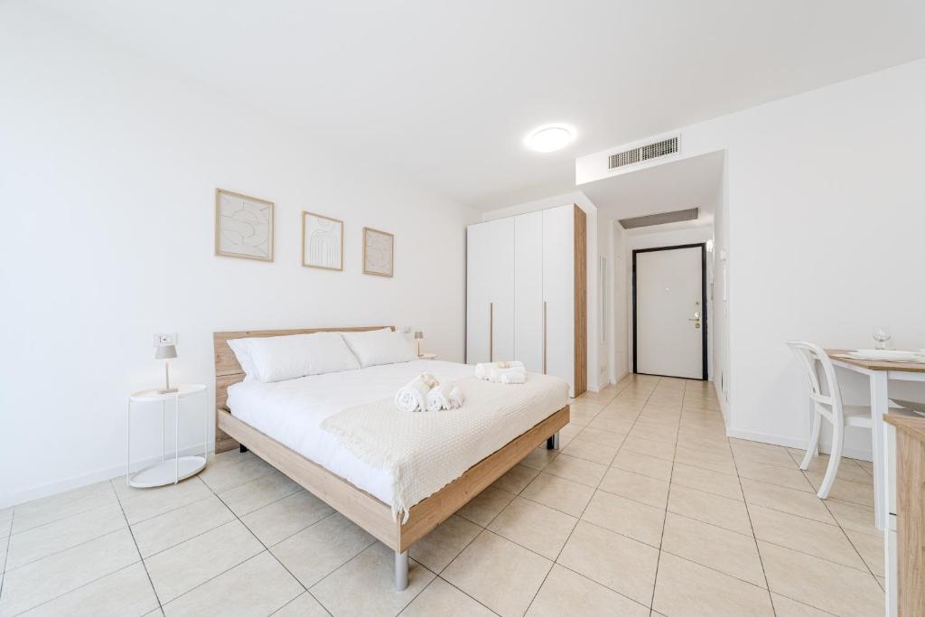 a white bedroom with a bed and a table at Martesana47 - 5 Min S Raffaele e Linate Apt in Vimodrone