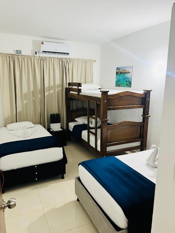 a room with two beds and a desk in it at Hotel Montserrat in Valledupar
