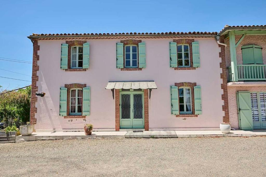 a pink house with green shutters on it at Gîte ferme équestre avec piscine in Castex