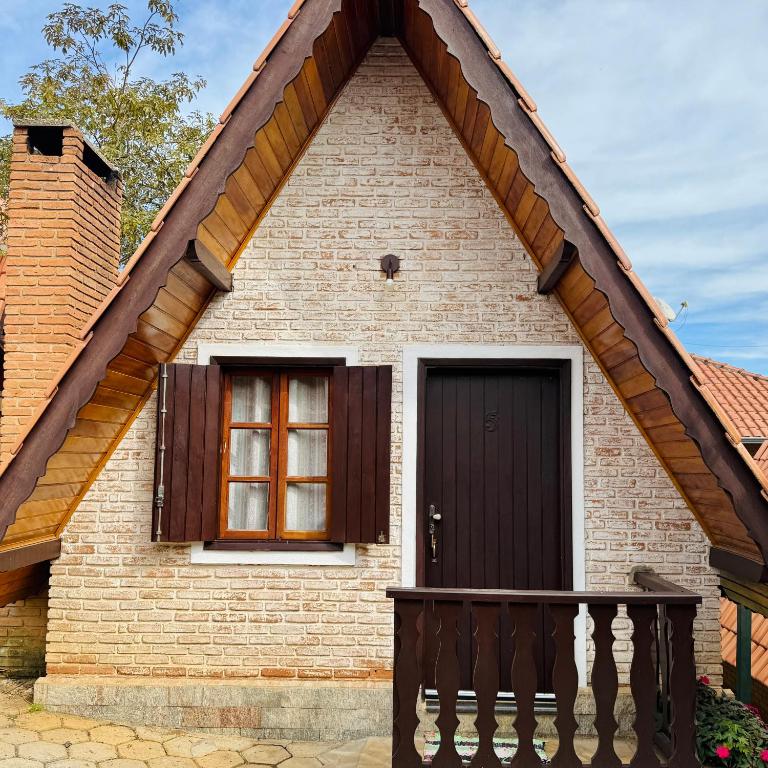 a house with a brown door and a balcony at Pousada Florada do Amanhã in Monte Verde