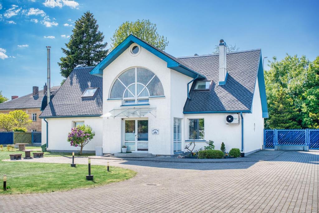 a white house with a blue roof at Jūras Vilks in Ventspils