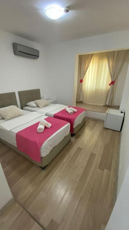 two beds in a room with wooden floors at orhan pansiyon in Çeşme