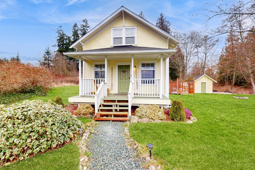 a small yellow house with a green door on a yard at Cozy Cottage w/ Hot Tub in Freeland, Pets Welcome! in Freeland