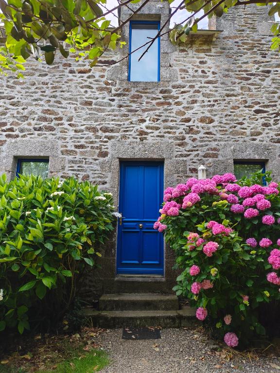 a blue door on a brick building with pink flowers at Les gîtes de Tréguennec in Tréguennec