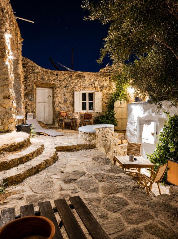 a stone building with a patio with benches and a table at Pyrgi Artemis Place in Mikonos