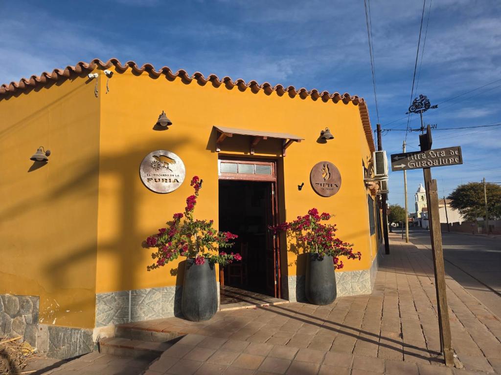 a yellow building with two flower pots in front of it at Descanso de la Furia in San Carlos