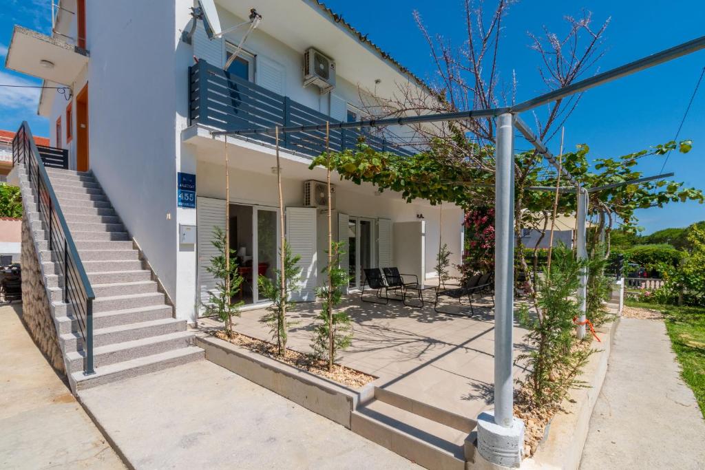 a white building with stairs and plants in front of it at Apartments Ian in Lopar