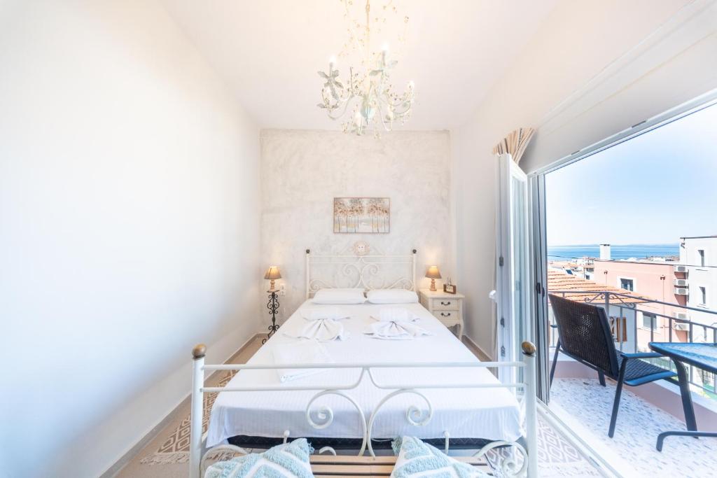 a white bedroom with a bed and a balcony at Socratous Apartments in Mytilene