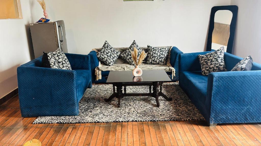 a living room with two blue couches and a table at The cosmos farm in Gurgaon